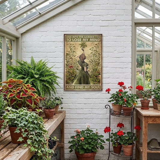 A vintage-style metal poster hangs on a white brick wall inside a bright greenhouse, surrounded by potted plants and wooden shelves. The poster features a woman in a green dress standing among flowers and the text, 'AND INTO THE GARDEN I GO TO LOSE MY MIND AND FIND MY SOUL'.